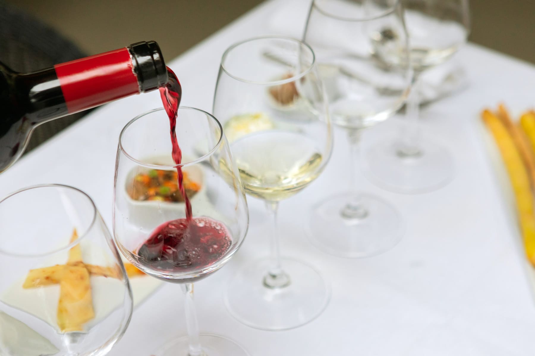 Vino rosso versato in un calice sopra un tavolo apparecchiato